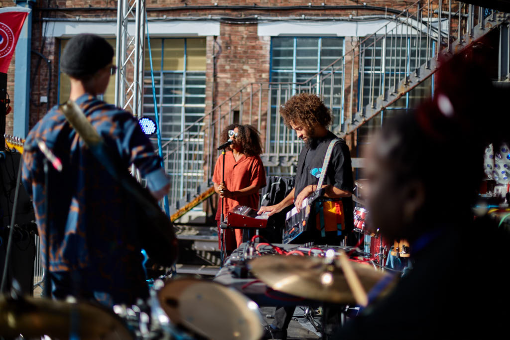 Band playing drums and guitar in a brick courtyard