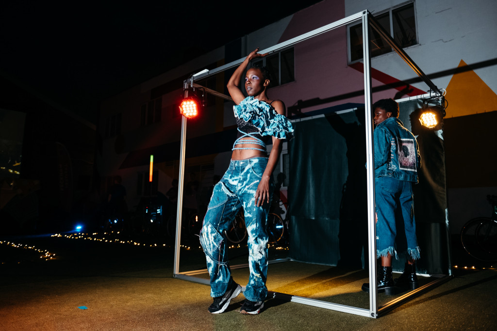 Dancer in denim performing outdoors at night beside a metal frame