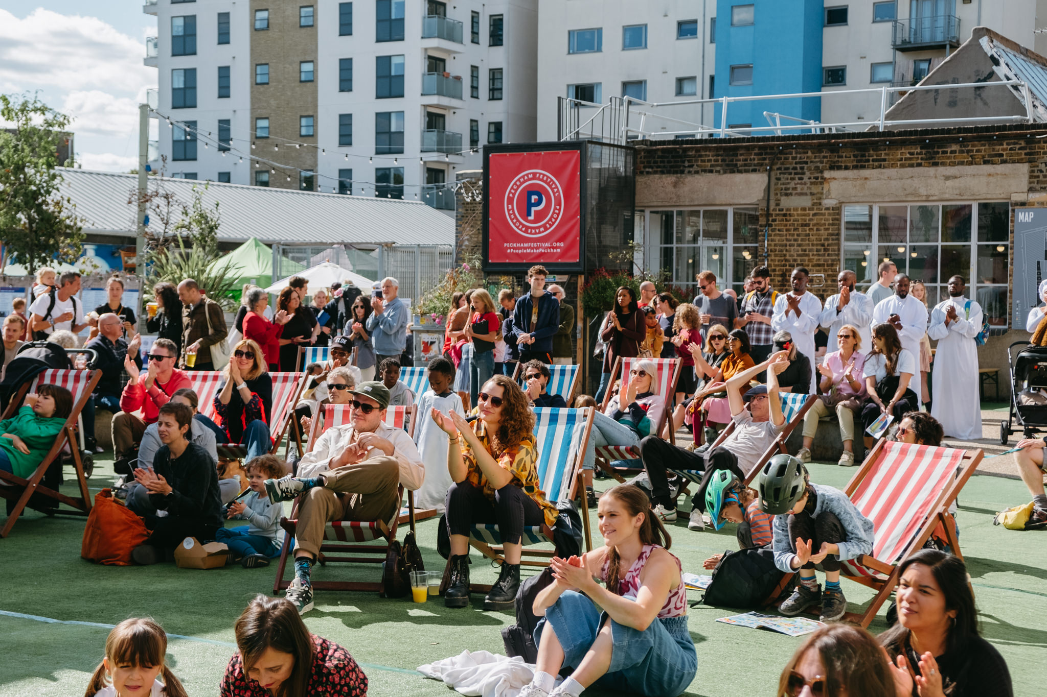 Crowd relaxing on deckchairs and the grass at an outdoor festival stage