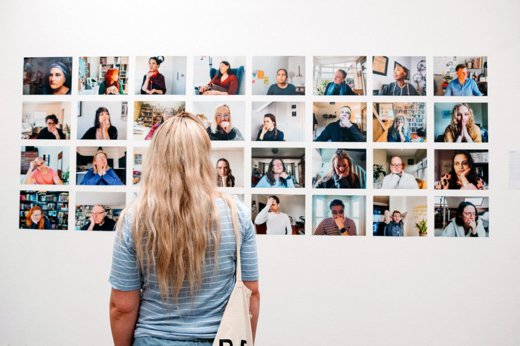 Visitor looking at a wall of portrait photographs in a gallery