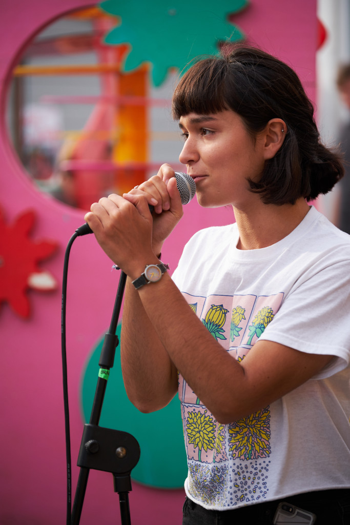 Singer performing into a microphone in front of a bright pink backdrop