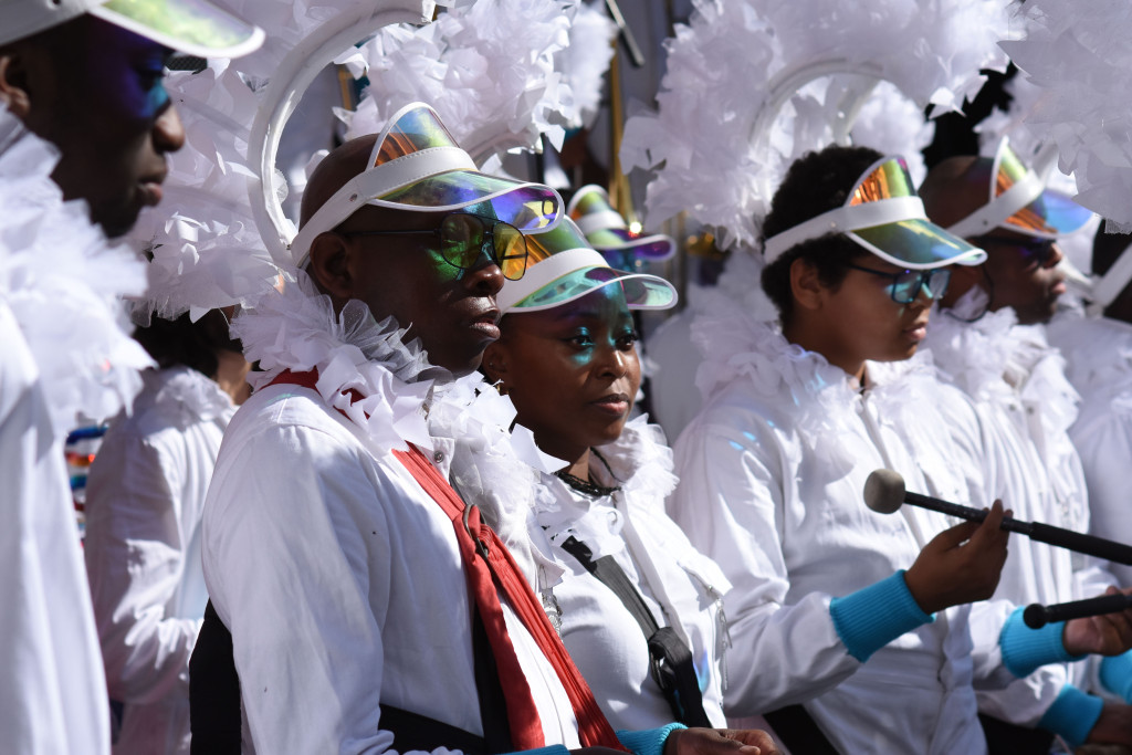 Steel pan players in white feathered costumes and visors